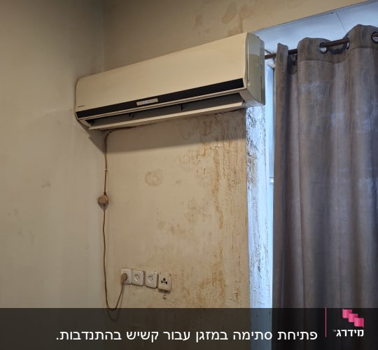 מזגן מותקן על קיר עם כתמי רטיבות